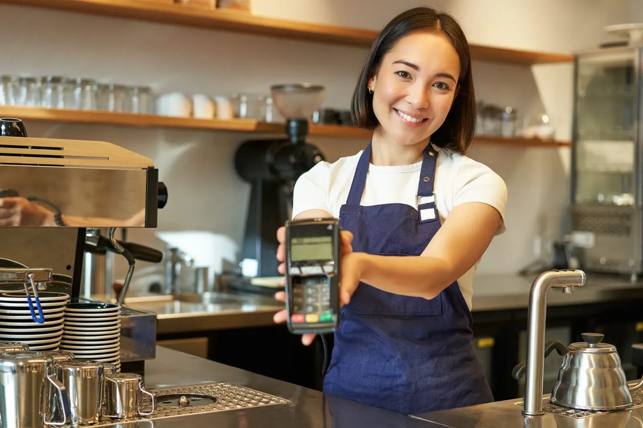 Barista podaje terminal płatniczy do zapłaty w kawiarni